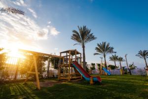 金马利奥特Tolip Family Club Borg El Arab的公园内一个带滑梯和棕榈树的游乐场