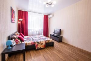 克拉斯诺达尔Апартаменты у Парка Краснодар на Восточно-Кругляковской的一间卧室配有床和红色窗帘的窗户