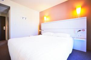 拉罗谢尔罗歇尔中心齐亚迪酒店 - 莱斯米尼蒙的酒店客房配有一张带两个枕头的大型白色床。