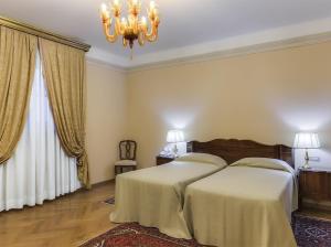 雷扎托福娜罗丽别墅皇宫酒店的一间卧室配有两张床和吊灯。