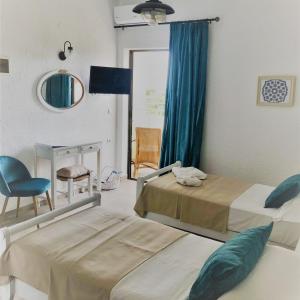 伊罗达Elounda George Studios的一间卧室配有两张床、一把椅子和镜子