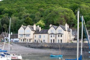 波洛克The Porlock Weir Hotel的一座白色的大房子,水中有船