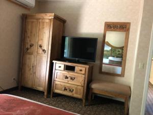 圣海伦娜艾尔波尼塔汽车旅馆的一间卧室配有电视和带镜子的梳妆台