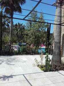 勒卡斯特雷特Appartement Domaine l'Oliveraie的棕榈树和游泳池的黑色围栏