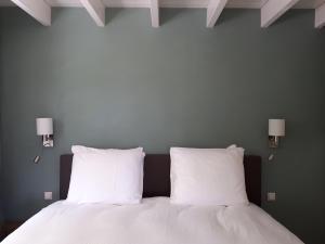 Hazerswoude-RijndijkLodges near the Rhine - Sustainable Residence的一张带两个白色枕头的床和墙上的两盏灯
