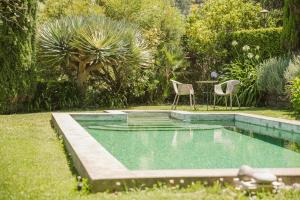 蓬塔杜帕戈Casa Da Muda的庭院内的游泳池,配有两把椅子和一张桌子