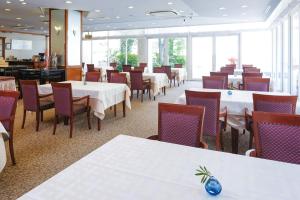 高松高松国际大酒店的餐厅设有白色的桌椅和窗户。