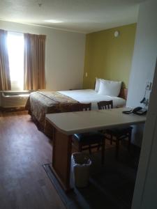 黑泽尔伍德Welcome Suites Hazelwood Extended Stay Hotel的配有一张床、一张桌子和一张桌子的酒店客房