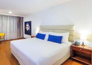 马尼萨莱斯Pop Art Hotel Manizales Centro Histórico的卧室配有带蓝色枕头的大型白色床