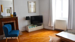 博讷Le Jardin Secret De Beaune的客厅配有电视和蓝椅