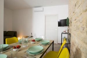 波扎洛Funduq ospitalità iblea的餐桌,配有绿色菜肴和黄色椅子