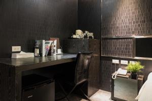 台北凡登东栈商务旅店的一张桌子和椅子,位于一间黑色瓷砖的房间