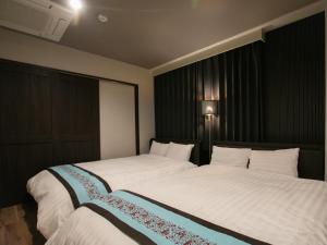 大阪BIG ROOM GUEST HOUSE的一间卧室配有两张带白色床单的床