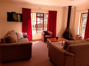 德尔斯特鲁姆Crane Cottage的客厅配有两张沙发和红色窗帘