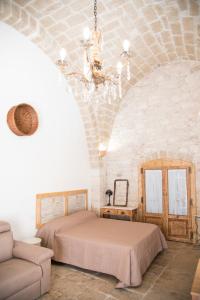 焦维纳佐Piazza Duomo - Medieval Puglia's House的一间卧室配有一张床、一张沙发和一个吊灯。
