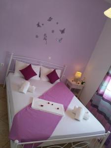 帕罗奇亚尼科莱塔客房酒店的一间小卧室,配有一张白色的床和紫色枕头