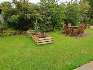 ShermanburyHoliday Home Woodhouse-4 by Interhome的花园设有木桌、椅子和草地。