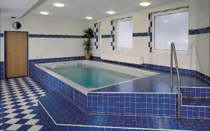 尼萨河畔亚布洛内茨布里吉酒店的一间蓝色瓷砖浴室,内设浴缸