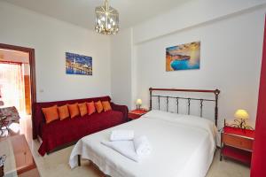 扎金索斯镇皮塔斯公寓的一间卧室配有一张床和一张红色的沙发