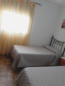 科尼尔-德拉弗龙特拉TRUJILLO HOLIDAY HOME con PISCINA的一间卧室设有两张床,窗户配有窗帘