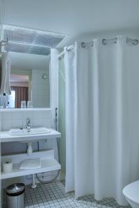 里希迈基Teatterihotelli Riihimäki的浴室设有白色的淋浴帘和水槽
