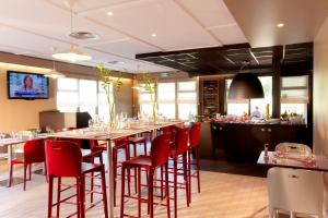 欧什坎姆盘奈奥彻酒店的餐厅设有长桌和红色椅子
