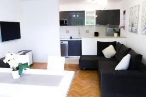 米利尼Villa Silvija的一间带黑色沙发的客厅和一间厨房