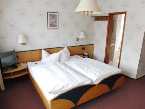 巴特欧波Hotel Olympia的卧室配有一张白色大床和电视。