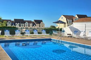 威尔斯海滨之村酒店的一个带椅子的游泳池和一个背景房子