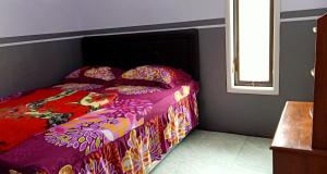 布罗莫Holiday Home Anggun Bromo的一间卧室配有一张带五颜六色棉被的床