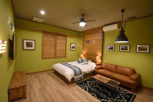 甲斐市Hotel Pinon - Adult Only的一间卧室设有绿色的墙壁、一张床和一张沙发