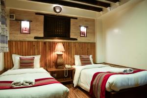 加德满都尼泊尔亭台酒店的一间卧室配有两张床和一张带台灯的桌子