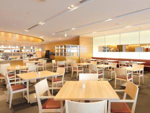 东京Haneda Excel Hotel Tokyu Haneda Airport Terminal 2的配有木桌和白色椅子的餐厅