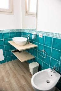 托尔托利B&B Il Viaggiatore的蓝色瓷砖浴室设有水槽和卫生间
