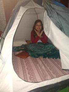 桑提科帕coorg camping tent stay的坐在帐篷里的床上的女人
