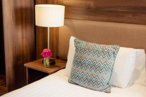 基拉尼斯科特斯酒店的一张带枕头的床和一张带台灯的桌子