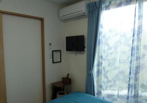 船桥市Kanaloa Funabashi的一间卧室设有一张床和一个带电视的窗户。