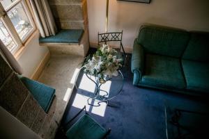 阿维拉洛维拉达宫酒店的客厅设有绿色沙发和带鲜花的桌子