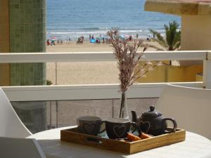 洛斯马蒂雷斯VORA GANDIA BEACH - Alquiler Familias的一张桌子,上面有2个杯子和托盘,享有海滩美景