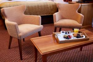 格拉茨克洛斯公牛酒店的一间房间,配有两把椅子和一张桌子上的食品托盘