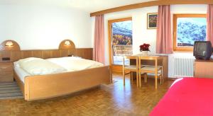 索尔达Hotel Alpenhof的一间卧室配有一张床、一张桌子和一台电视