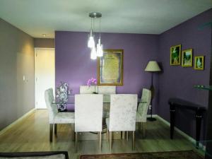 里约热内卢Apartamento Vila DR - Barra da Tijuca,prox Jeunesse,Arenas,Rio Centro,praias, Shopping的一间设有桌椅和紫色墙壁的用餐室