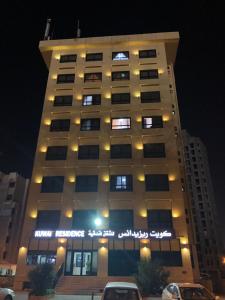 科威特科威特公寓的一座高高的建筑,晚上有车停在前面