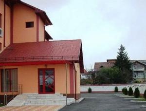 拉姆尼库沃尔恰玛利亚酒店的一座红色屋顶的建筑和一个停车场