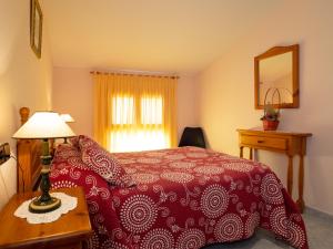 El Pueyo de AraguásApartamento Casa Dueso的一间卧室配有红色的床和一张带台灯的桌子