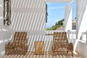 普恩达Ciel Villas Paros的门廊上的两张藤椅,享有海景