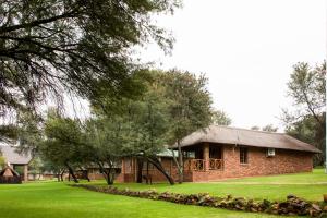 波切夫斯特鲁姆Elgro River Lodge的砖砌的建筑,有草地和树木