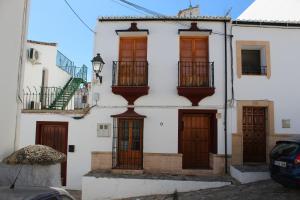 隆达La Casita Gris的白色的房子,设有木门和阳台