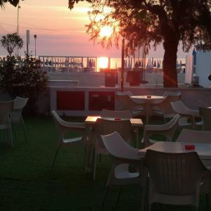 阿布鲁齐的罗塞托玫瑰草酒店 的一组桌椅,背景是日落