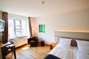 海德堡Qube Hotel Bergheim的酒店的客房 - 带一张床、椅子和窗户